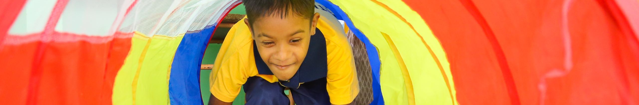 A child playing in a colourful sensory tunnel